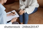 Unrecognizable Psychologist Talking With Female Client Taking Notes During Psychotherapy Session Sitting In Office. Selective Focus, Cropped