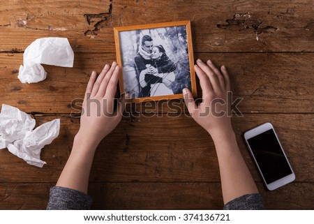 Unrecognizable sad woman holding broken picture of couple in love. 