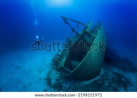 A unrecognizable scuba diver explores a sunken shipwreck at the bottom of the mediterranean sea, Greece