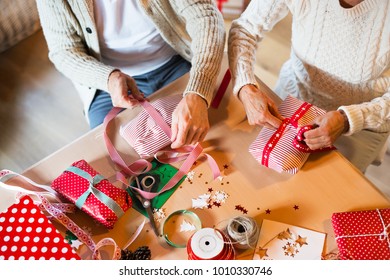 Unrecognizable senior couple in sweaters wrapping Christmas gift - Powered by Shutterstock