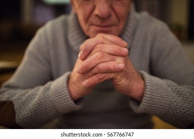 Unrecognizable senior man at home praying, hands clasped togethe - Powered by Shutterstock