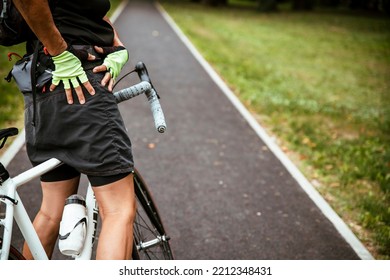 Unrecognizable Senior Woman Cyclist  With Hip Pain Standing By The Bike Holding And Massaging Injury. Copy Space