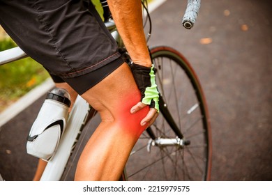 Unrecognizable Senior Woman Cyclist Holding Hand On Knee In Pain, Massaging Her Gliding Joint Bone. Arthritis Cramp In The Knee While Cycling Outdoor. Painful Spot Highlight In Red. Copy Space