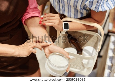 Unrecognizable shop assistant using cream tester to show its texture to customer