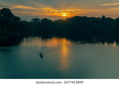 Unrecognizable silhouette of a man paddling a canoe in the Amazon rainforest at sunrise, Yasuni national park, Ecuador. - Powered by Shutterstock