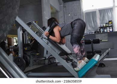 Unrecognizable Sportswoman Doing Buttocks Workout In Hack Squat Gym Machine