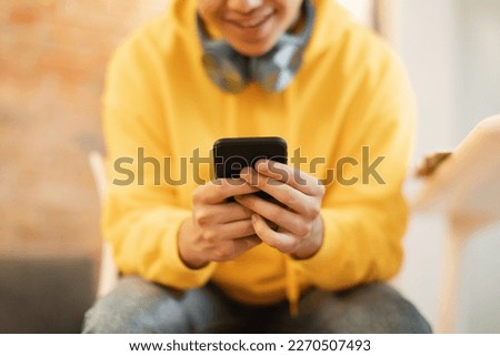 Unrecognizable Teen Boy Using Phone Playing Mobile Games Online And Texting In Social Media Application Sitting Indoors. Teenagers And Gadgets Lifestyle. Cropped, Selective Focus On Smartphone