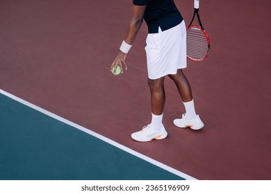 An unrecognizable tennis player bouncing a ball at baseline before serve - Powered by Shutterstock