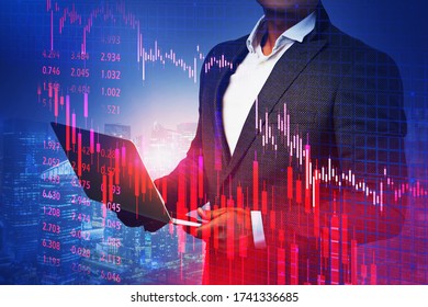 Unrecognizable trader using laptop in blurry night city with double exposure of falling financial chart. Concept of crisis and stock market. Toned image double exposure