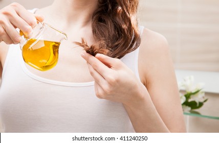 Unrecognizable Woman Applying Oil Mask To Hair Tips In A Bathroom; Beauty And Haircare Concept