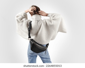 Unrecognizable Woman From Behind Wearing White Oversized Sweater and Black Genuine Leather Fanny Pack Cross Body. Winter Season Fashionable Look