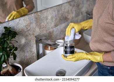 Unrecognizable woman cleaning bathroom tap with vinegar - Shutterstock ID 2154094277