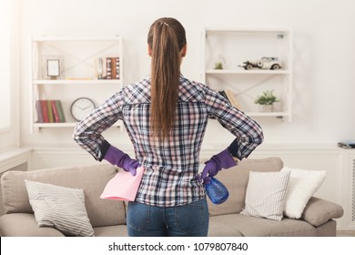 Unrecognizable woman with cleaning equipment ready to clean house. Cropped girl holding rag and spray detergent, professional cleaning service concept, copy space, back view