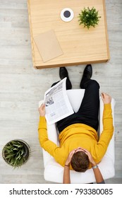 Unrecognizable Woman Closed Eyes Of Her Boyfriend With Hands While Standing Behind Him, He Sitting On Cozy Armchair And Holding Newspaper, Directly Above View