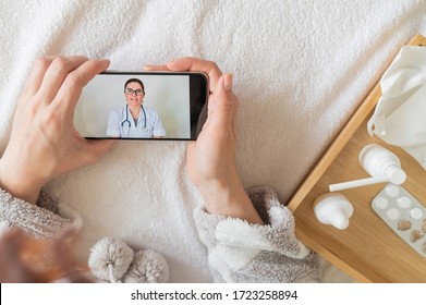 Unrecognizable Woman With A Cold Talking To A Doctor Through Video Chat On A Smartphone. Friendly Doctor Gives An Online Consultation To The Patient.