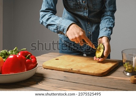 Unrecognizable woman crisscross cutting avocado in the kitchen