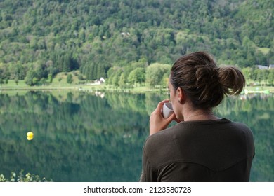 Unrecognizable Woman Drinking Coffee In Front Of The Lake Of Her Rural Accommodation