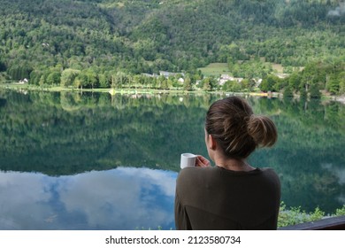 Unrecognizable Woman Drinking Coffee In Front Of The Lake Of Her Rural Accommodation