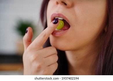 Unrecognizable woman eats green grape. Close up of part of female face with berry