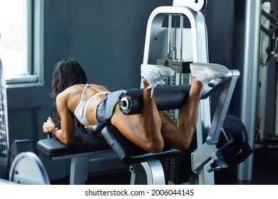 Unrecognizable woman exercising with leg curl machine in gym