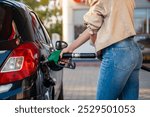 Unrecognizable woman fills up car tank on the gas station 