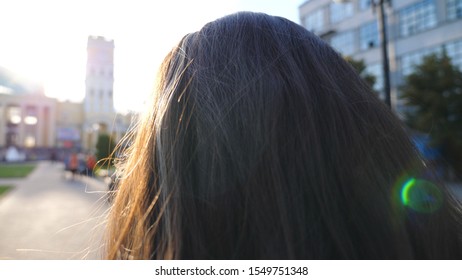 Unrecognizable Woman Going To Work And Straightening Hair At Early Morning Street. Pretty Girl Having Stroll Through City Street On Way To Job. Sunlight Illuminating Hair Of Charming Brunette. Slow Mo