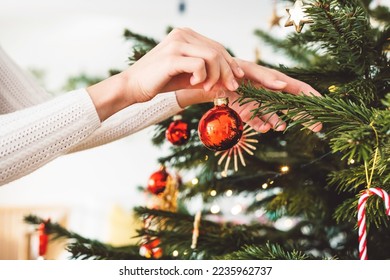 Unrecognizable woman hand putting an ornament on the Christmas tree - Powered by Shutterstock