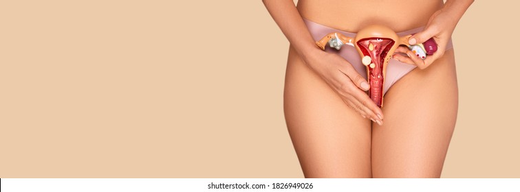 unrecognizable woman holding the anatomical model of uterus and ovaries with pathology on a beige background. Diseases uterus and ovaries, menstruation