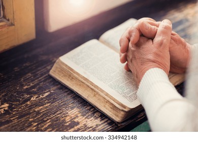 Unrecognizable woman holding a bible in her hands and praying