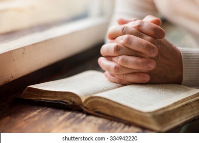 Unerkennbare Frau, die eine Bibel in ihren Händen hält und betet
