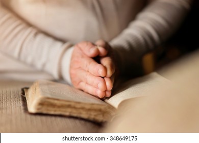 Unrecognizable woman holding a bible in her hands and praying