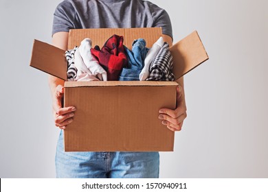 Unrecognizable woman holding box with clothes in it. close-up. Clothing donation. - Powered by Shutterstock