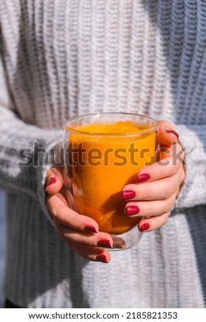 Unrecognizable woman holding Pumpkin smoothie spiced latte. Autumn coffee with spicy pumpkin flavor seasonal hot drink. Fall Drinks for Halloween and Thanksgiving. Vegan healthy dieting food