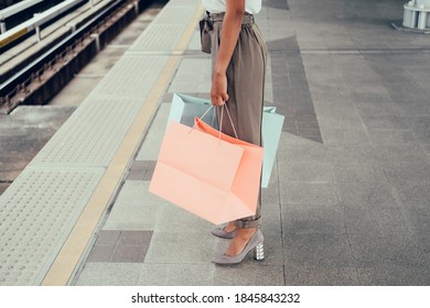 Unrecognizable Woman Holding Shopping Bags, Standing And Waiting On Subway Station. Legs Only