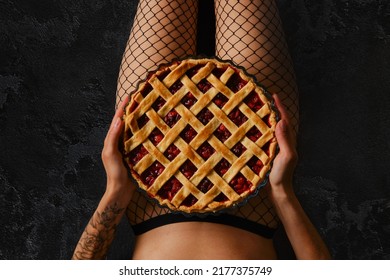 Unrecognizable woman holds cherry pie on her hips in fishnet tights