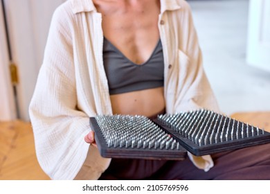 Unrecognizable Woman holds sadhu board close-up, cropped lady is going to practice yoga exercises Sadhu. Alternative medicine. Sadhu foot board. Yoga relaxation practice training