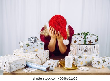 Unrecognizable woman housewife tired of wrapping Christmas presents in home. Stacks of gifts. Seasonal holidays depression concept.