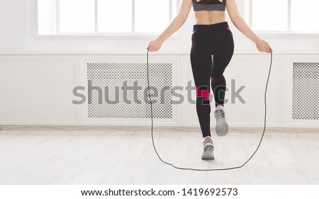 Unrecognizable woman jumping over the skipping rope in studio, crop, panorama, free space