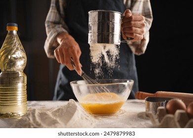 Unrecognizable woman kneading dough on table. Female hands sifting flour into transparent bowl. Selective focus. - Powered by Shutterstock