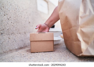 Unrecognizable Woman Leaving Cardboard Box With Dinner On A Stone Bench