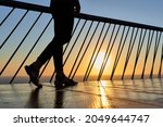 Unrecognizable woman legs walking on a bridge at dawn