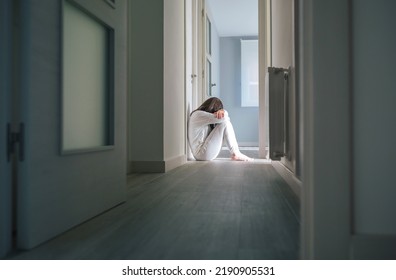 Unrecognizable Woman With Mental Disorder In Pajamas Sitting On The Floor Of A Mental Health Center