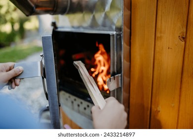 Unrecognizable woman putting piece of wood in outdoor hot tub. Close-up. - Powered by Shutterstock