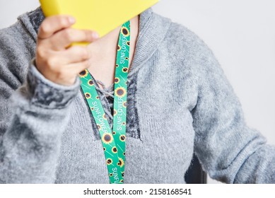 Unrecognizable Woman Reading A Yellow Book, Studying At Home, Using A Sunflower Lanyard, Symbol Of People With Invisible Or Hidden Disabilities.