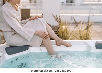 Unrecognizable woman relaxing in the outdoors bathtub. Female spend morning time in swimming pool. Bathtub with hydromassage jets and blue water in hot tub. Spa treatment, wellness concept