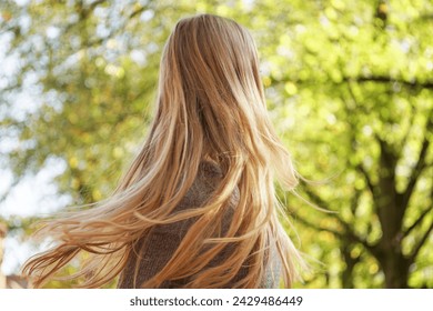 unrecognizable woman shaking her long blond hair outdoors in spring - Powered by Shutterstock