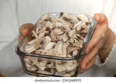 Unrecognizable woman showing into camera frozen food sliced mushrooms champignon homemade. Harvesting concept. Stocking up vegetables for winter storage - Powered by Shutterstock