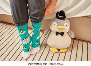 Unrecognizable woman sitting on bed wearing funny penguin socks