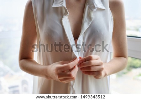 Unrecognizable woman unbuttoning white blouse at home. Foto d'archivio © 