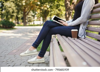 Unrecognizable woman using digital tablet. Girl working outdoors on portable computer, copy space. Technology, communication, freelance and remote working concept.